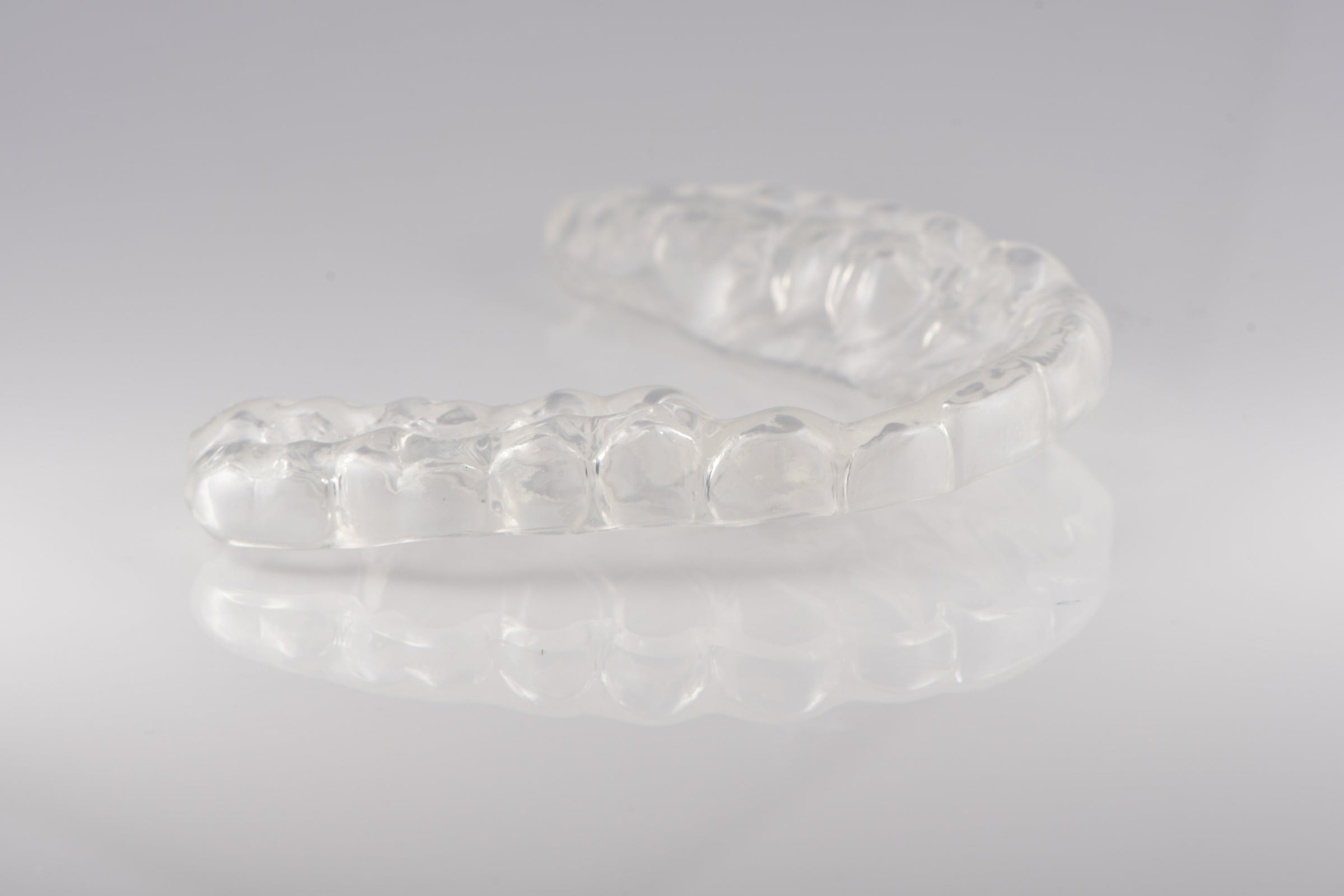Clear orthodontic retainer on a gray background