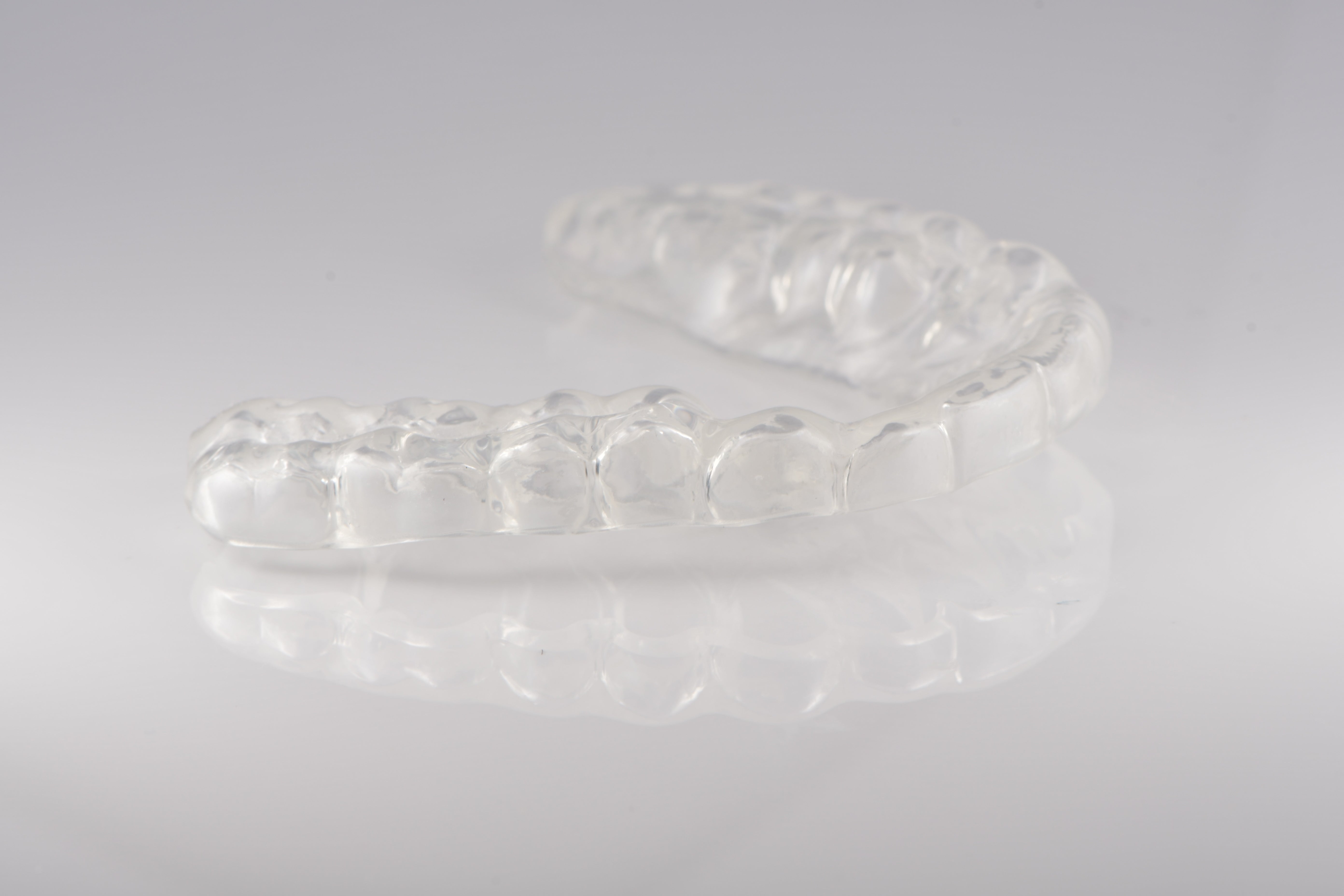 Clear orthodontic retainer on a gray background